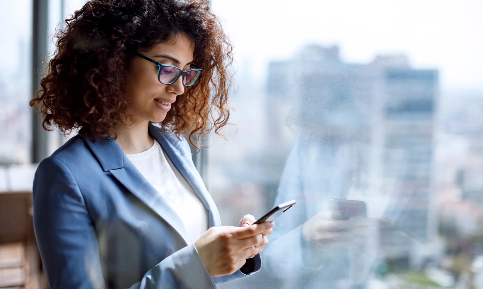 Businesswoman using smartphone by the window smaragd-image-home-01.jpg
